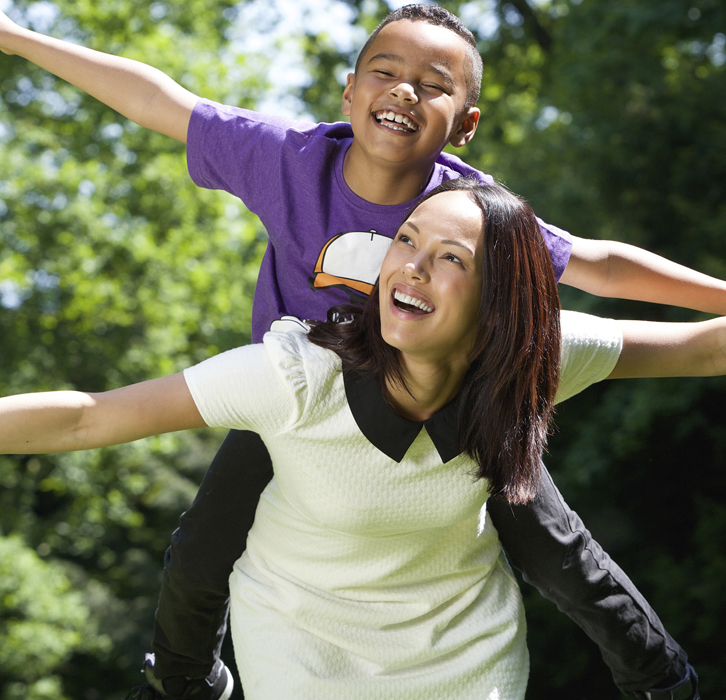 Mother giving her son a piggy-back ride, smiling - Theraplay