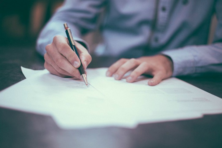 Person holding a pen and writing on a piece of paper